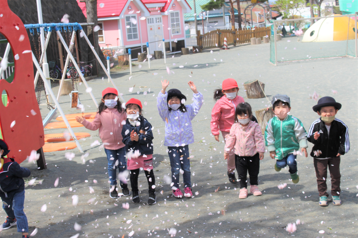 拾った桜の花びらを投げて遊ぶ子どもたちの様子
