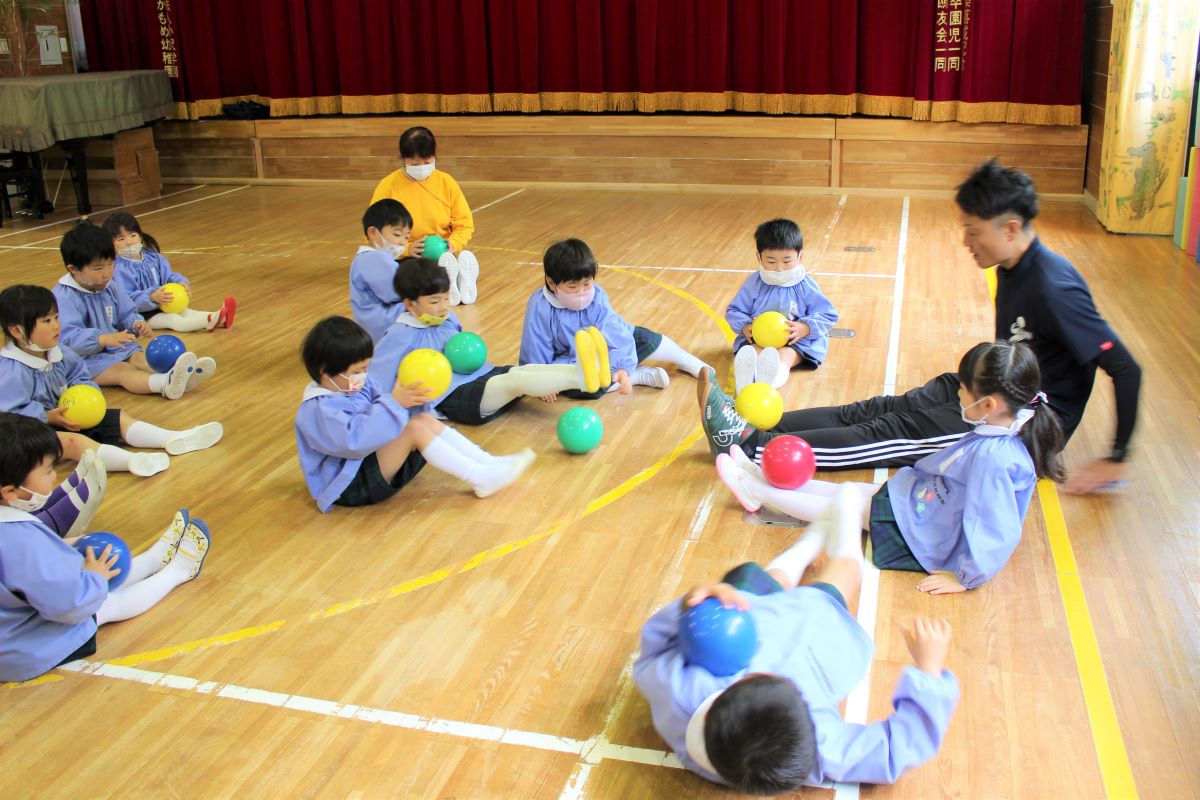 先生のお話を聞きながらボールを使って活動する4才児の様子（体育教室）