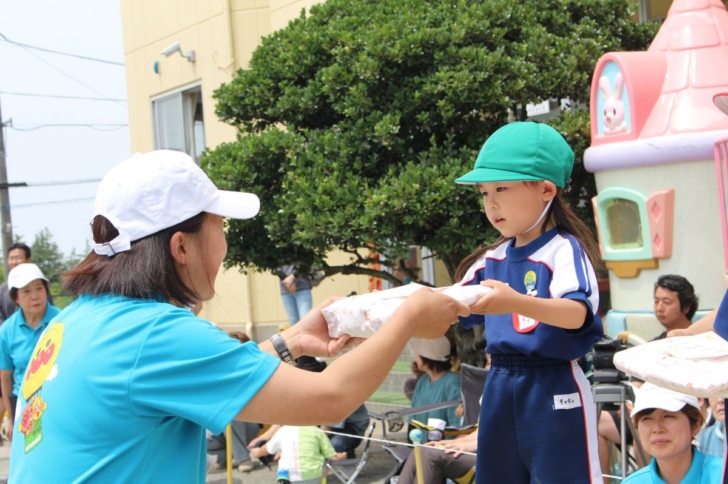 閉会式で園長先生より賞状とおみやげをいただく3才児女の子