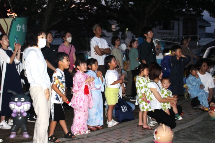 夕涼み会にて、打ち上げ花火を眺める親子の様子